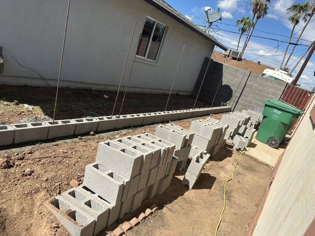 New block wall being built at a Phoenix, AZ home: first course of block set on the footing with vertical rebar
